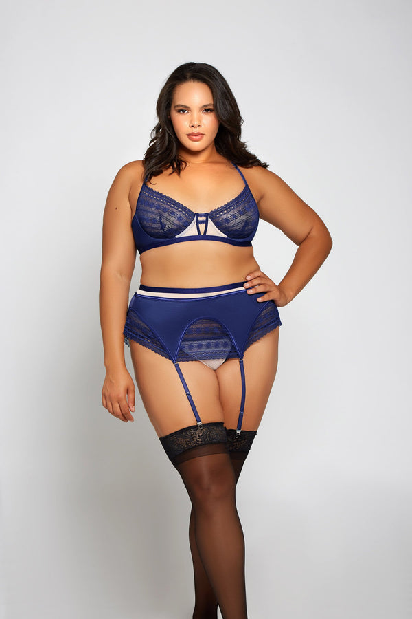 Plus size model wears a navy blue lace overlay bra with matching waist cincher.